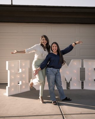 Damie celebrating with a buyer beside HOME marquee letters